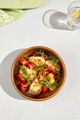 Crispy Fried Halloumi Cheese with Juicy Tomatoes and Fresh Arugula in a Wooden Bowl