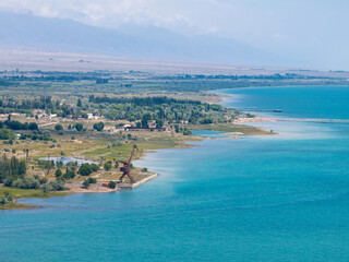 Drone view of the seashore from the sea. Old port crane and vivid landscape. Highland Issyk-Kul...