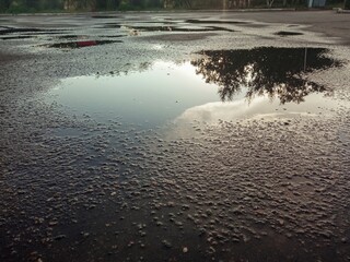 A puddle on the asphalt in the city. Rainy weather. Cloudy weather. The rainy season. Uneven...