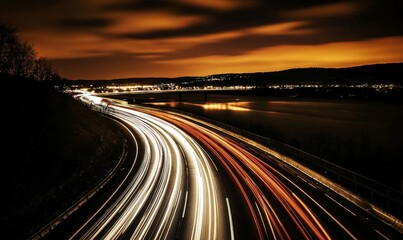 Obraz premium Long exposure photograph of car light trails on the highway at night with a river in the background.