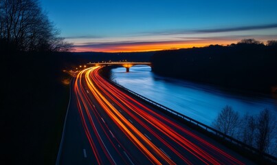 Obraz premium Long exposure photograph of car light trails on the highway at night with a river in the background.