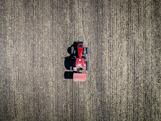 bird’s view of the red tractor with fertilizer spreader working on the field