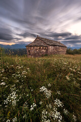 Iglesia de piedra con flores y cielo nuboso