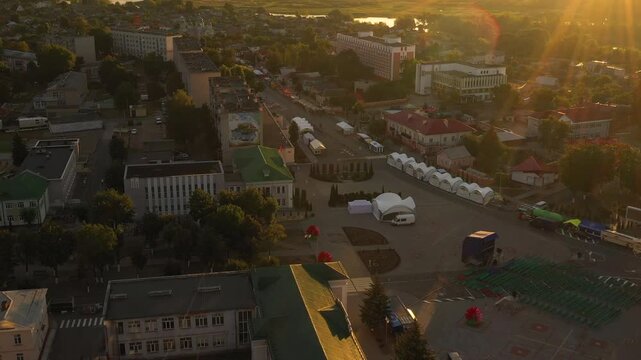 Aerial view of a sunlit urban area with a wellorganized tent setup beside a vibrant cityscape. Dobrush town, Belarus
