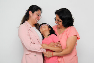 Three generations of brunette Latina women with glasses, grandmother, mom and daughter hug each other and show their love to celebrate Mother's Day