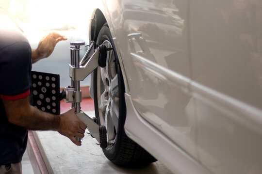 A technician placing sensors on the tires for wheel alignment. Technician performing 3D wheel alignment using a diagnostic system for camber and toe adjustments