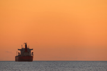 Fototapeta premium Cargo ship at sunset, with negative and copy space. Iron ore, or agricultural goods (wheat and canola) transportation