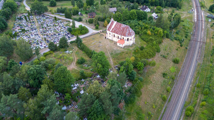 Drone photography of a graveyard surrounded by forest during summer cloudy day.