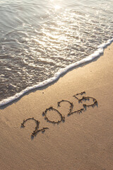 Written text 2025 on the sea beach at sunrise.