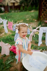 little girl playing  in a garden, washing clothes