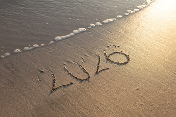 Happy New Year 2026 text on the sea beach.