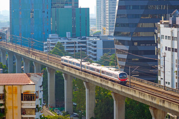 Modern train metro viaduct moving on rails above the ground in the city skyscrapers. Subway cars traveling across the bridge, public rapid transit.
