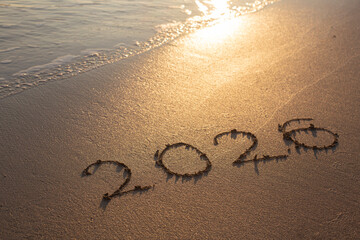 Happy New Year 2026 text on the sea beach.