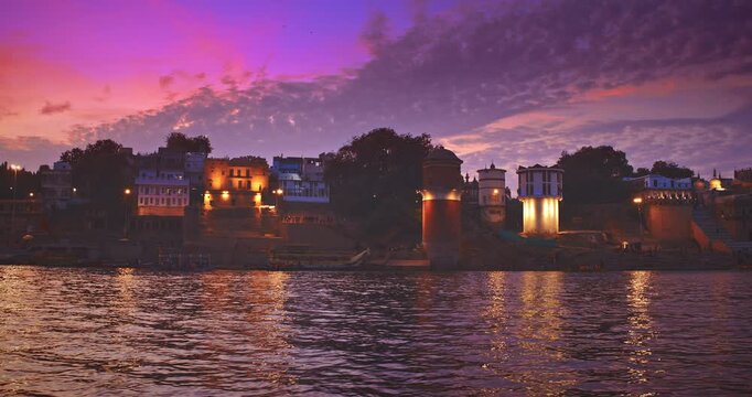 Varanasi, India. Many Boats Moored On Ganga River Near Ghats. Camera Moving Along Riverbank Embankment. General View On Lassi Ghat, Tulsi Ghat and Bhadaini Ghat. Purple Sunset Sky At Evening Time