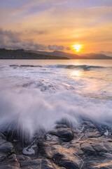 Sunset over the Cantabrian Sea at Lastron beach, Zierbana, Bizkaia with the waves between the rocks on the shore