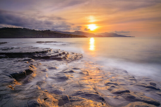 Sunset over the Cantabrian Sea at Lastron beach, Zierbana, Bizkaia with the waves between the rocks on the shore