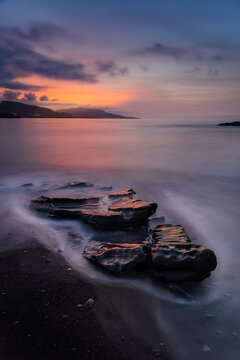 Sunset over the Cantabrian Sea at Lastron beach, Zierbana, Bizkaia with the waves between the rocks on the shore