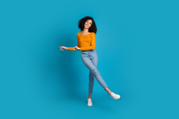 Full body photo of attractive young woman dancing have fun dressed stylish yellow clothes isolated on blue color background