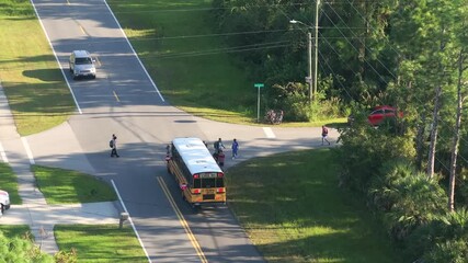 Students boarding school bus at bus stop before going to lessons standing in line. Coming back to school in new educational year semester. Public school transportation in the USA.
