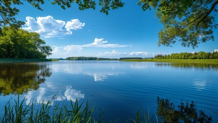 A Tranquil Bliss: Nature's Reflection on a Calm Lake Amidst a Clear Blue Sky and Lush Greenery Breathing Life into Every Corner of This Stunning Landscape Scene.