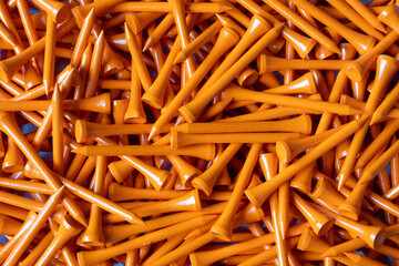 A large pile of Neon Orange Wooden Bamboo Golf Tees in a box