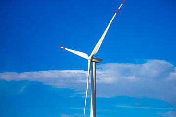 Fleet of power generators in motion. The blades of the wind farm rotate against the sky. The concept of extracting electricity from renewable sources. Wind turbine to generate electricity.