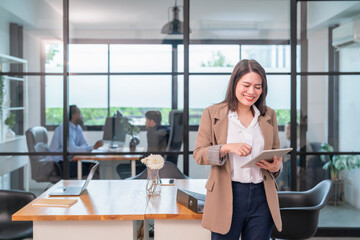 portrait young businesswoman standing at office desk working on digital tablet,multiracial business people,office workers on background