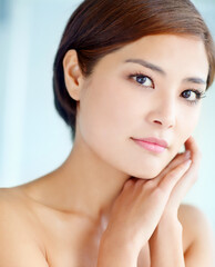Obraz premium Asian woman, portrait and feel for skincare, dermatology and beauty in studio with healthy skin. Female person, face and hygiene routine on blue background for facial treatment, self care and glow