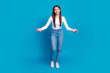 Full body photo of attractive teen woman stretch hands welcome dressed stylish white clothes isolated on blue color background