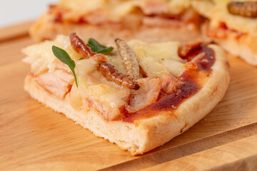 Close-up, Mouthwatering gourmet insect pizza, freshly baked and beautifully presented on a wooden cutting board. The pizza is adorned with a variety of toppings, including fresh basil leaves,