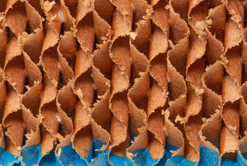 Abstract,  The evaporative-cooling-pad paper image shows a close-up view of a rough, textured surface made up of overlapping and interlocking shapes in shades of brown and blue