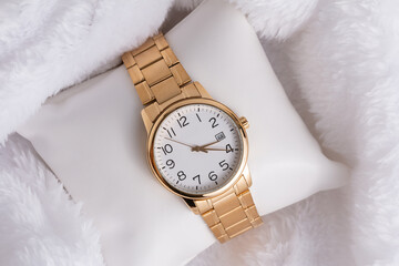 Gold luxury wristwatch, Made of a gold-toned metal on a white background with depth of field. Top view