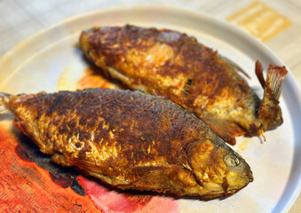Fried fish on a plate on the table. Fish after smoking on fire. Smoked fish cooked on smoke in a smokehouse.