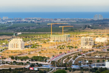 Construction site with tower crane, aerial view. House and buildings construction in Sagunto, Spain. Housing renovation, real estate.