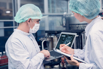 Food and Drink factory worker working together with hygiene monitor control mix ingredients machine with laptop computer