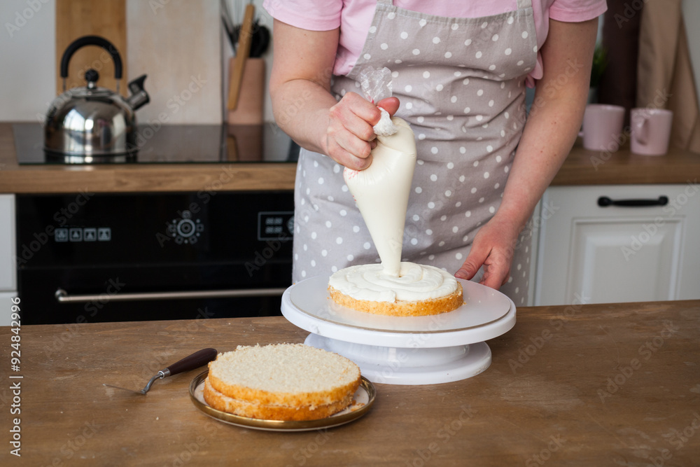 Wall mural woman in an apron in the kitchen preparing a cake