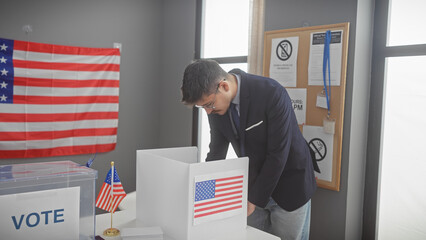A young hispanic man in a suit voting at a us polling station with an american flag in the...