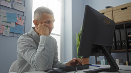 Man working at computer in office showing focus and concentration