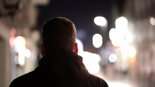 Mann geht nachts mit Jacke die Strasse entlang
