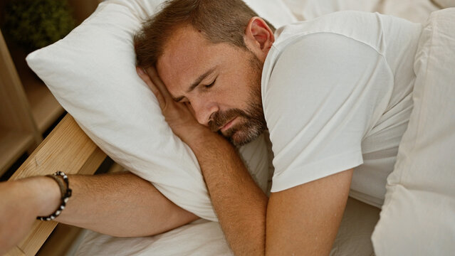 Hispanic middle-aged man with grey hair sleeping in a bedroom, portraying rest, comfort and wellbeing. - Powered by Adobe