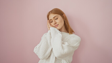 A serene young woman with red hair in a white sweater, dreaming against a pink background, evokes a...