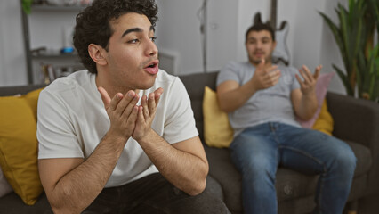 Two hispanic men having a lively discussion in a modern living room setting, expressing emotions...