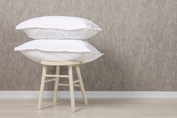 Many soft pillows on chair near grey wall. Space for text