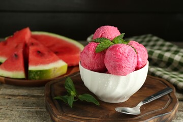 Scoops of tasty watermelon sorbet in bowl, fresh fruit, mint and spoon on wooden table