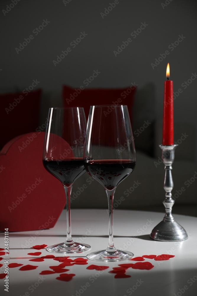 Wall mural burning candle, wine in glasses and paper hearts on table indoors