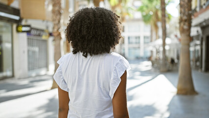 Back view of an african american woman with curly hair outdoors in a city