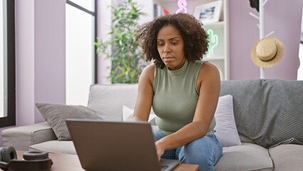 African american woman using laptop at home on the sofa