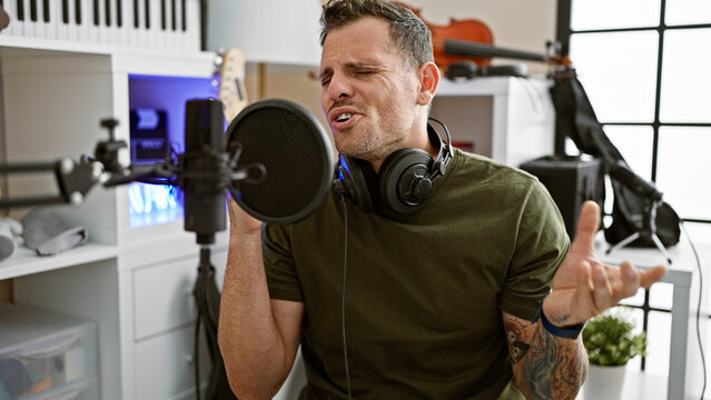 Hispanic man singing passionately in a music studio with a microphone and headphones
