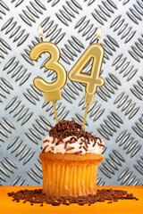 Chocolate cupcake with candle number 34 - Birthday on industrial metallic background.