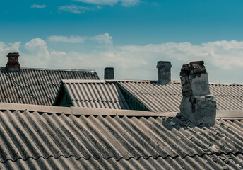 roofs and chimneys of old houses against the blue sky and white